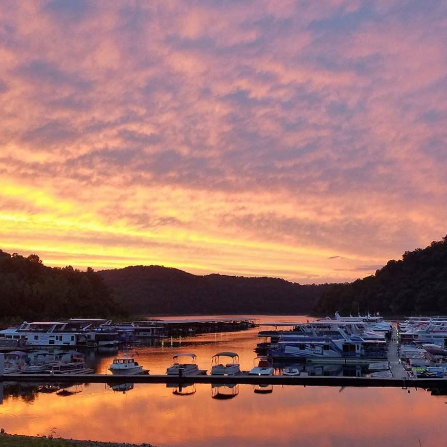 A view of boat slips at the Sligo Marina on Center Hill Lake during a pink and orange sunset reflecting on the lake.