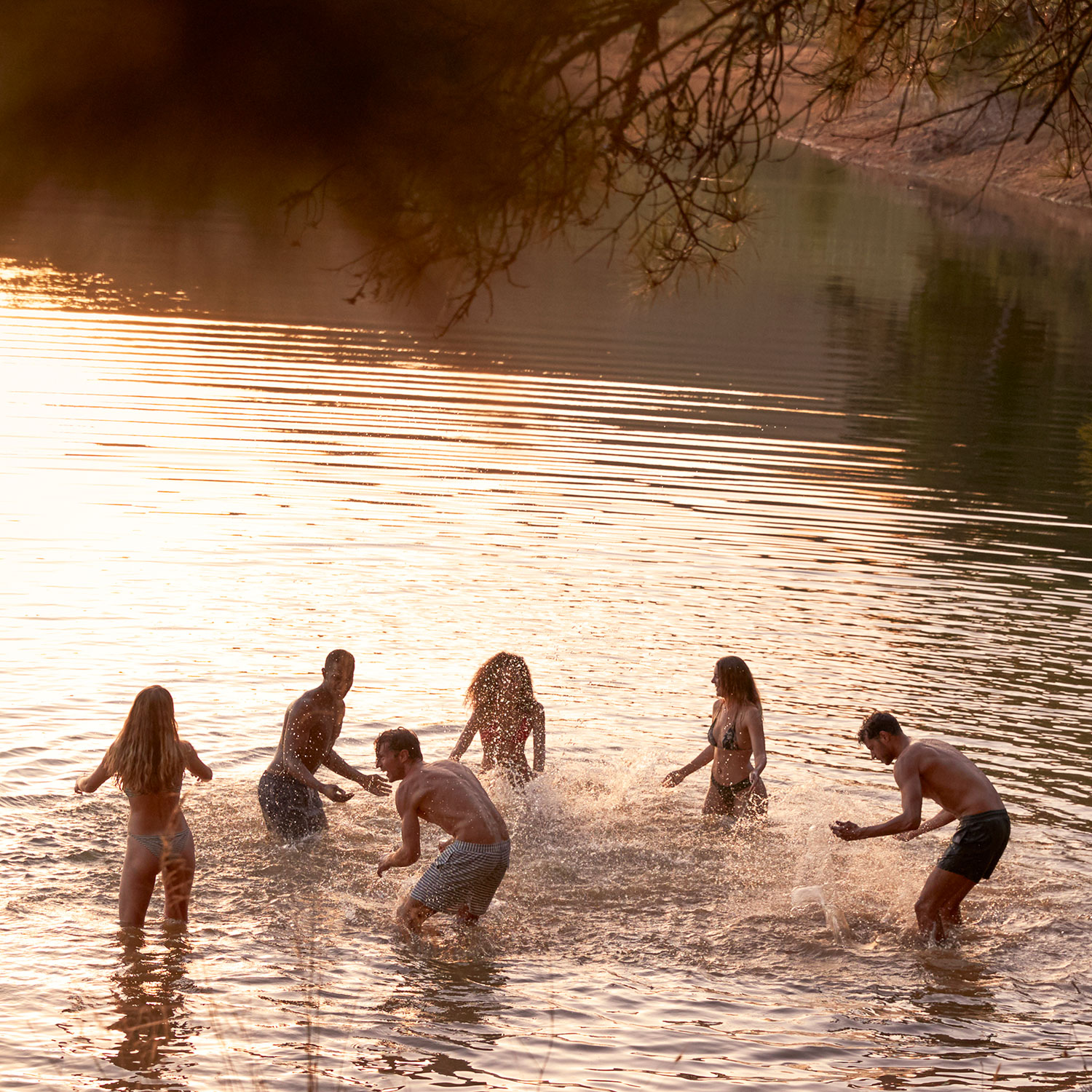 Young adult friends splashing and having fun at a Lake