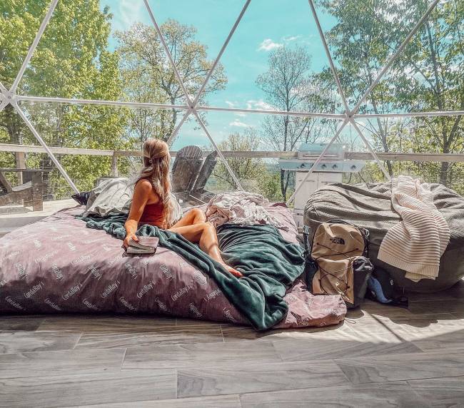 Woman sitting on a bed in a glamping dome near Nashville, TN