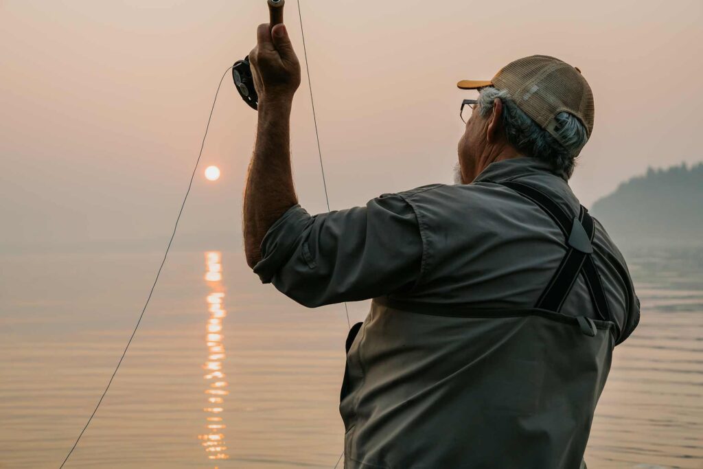 Senior man casting a fishing line at sunrise over Center Hill Lake, capturing the peaceful magic of early morning fishing.